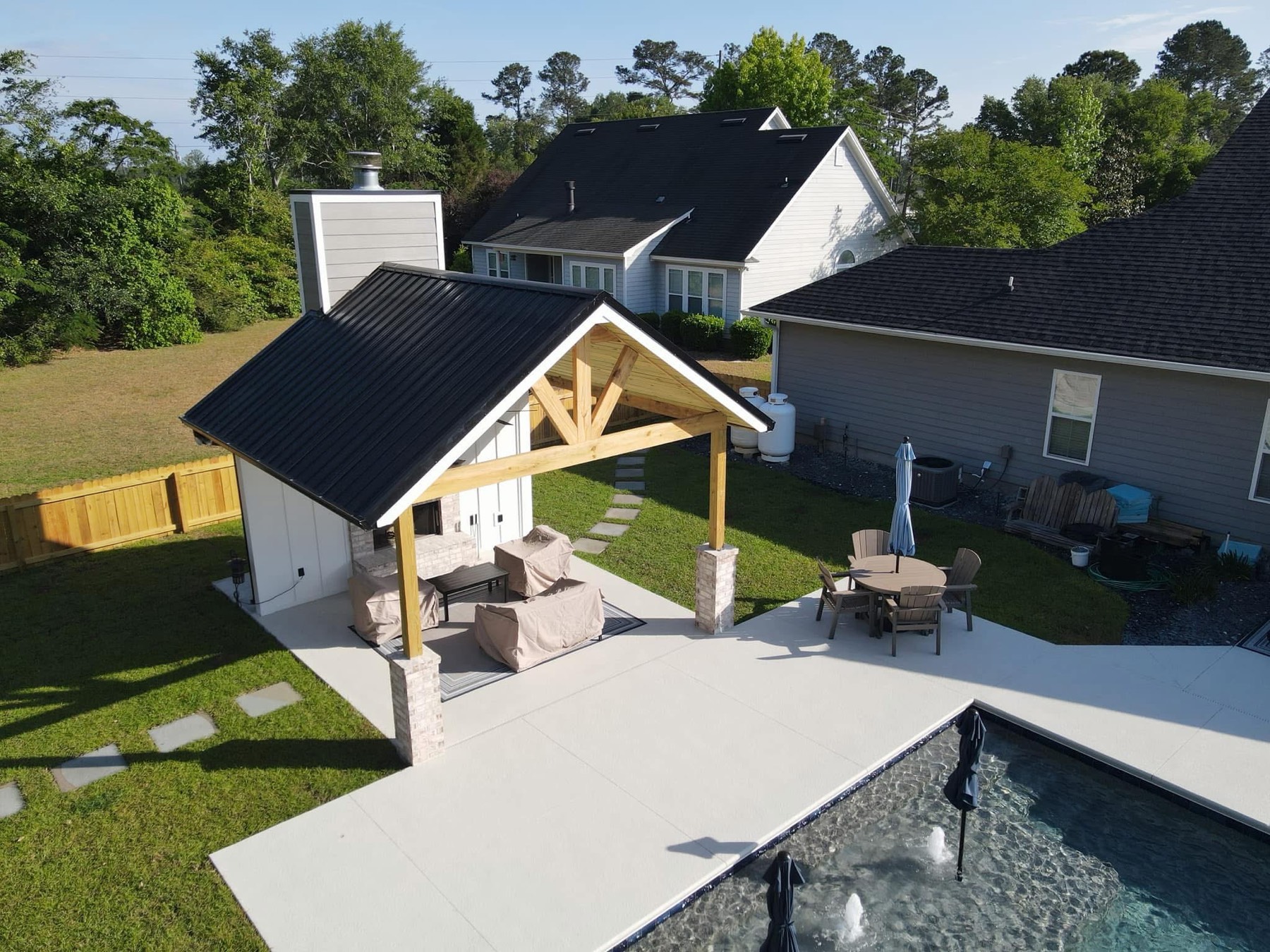 Pavilion with timber trusses, outdoor fireplace, and metal roof
