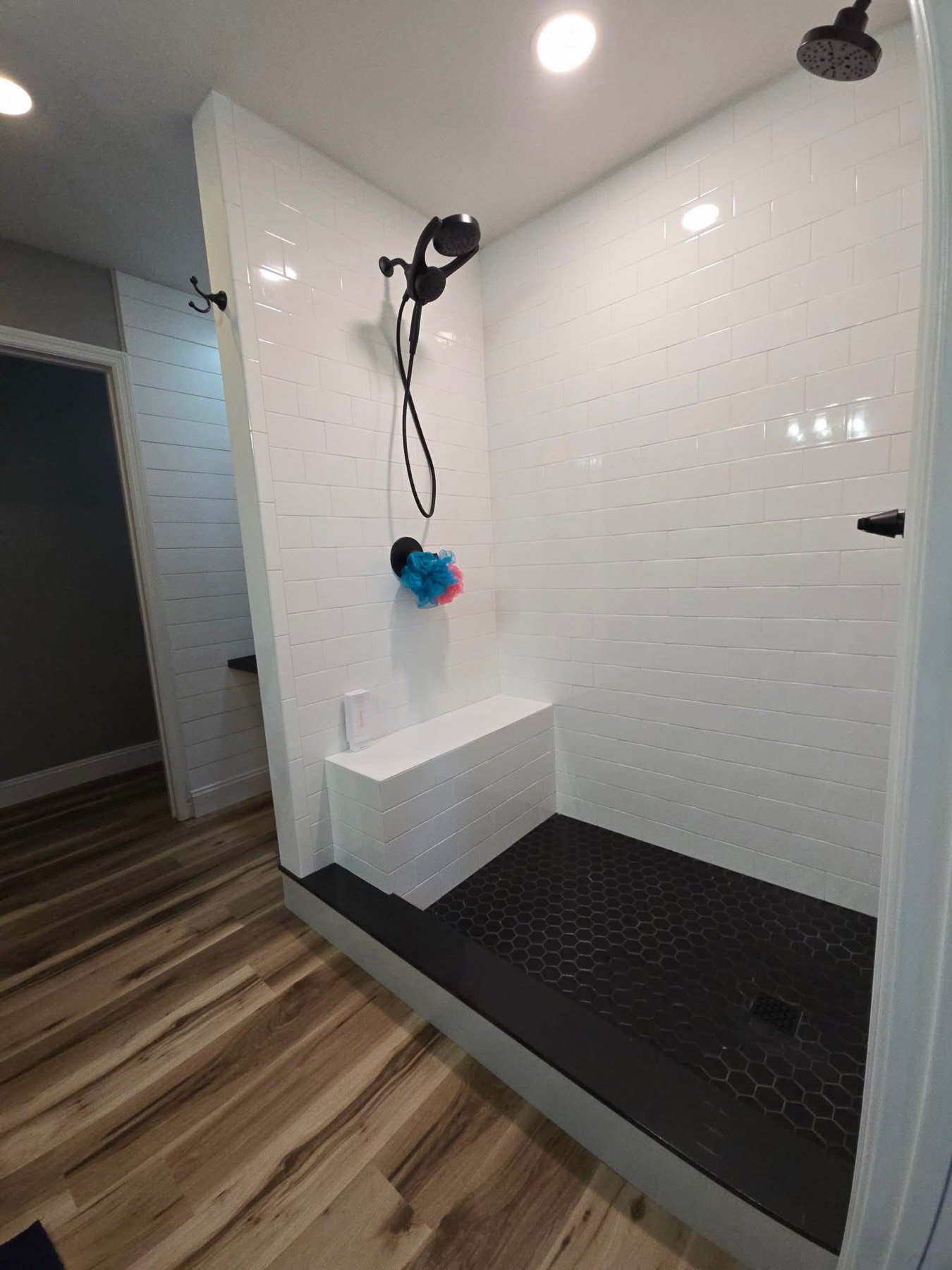 Walk-in shower: subway tile, black hex floor, bench
