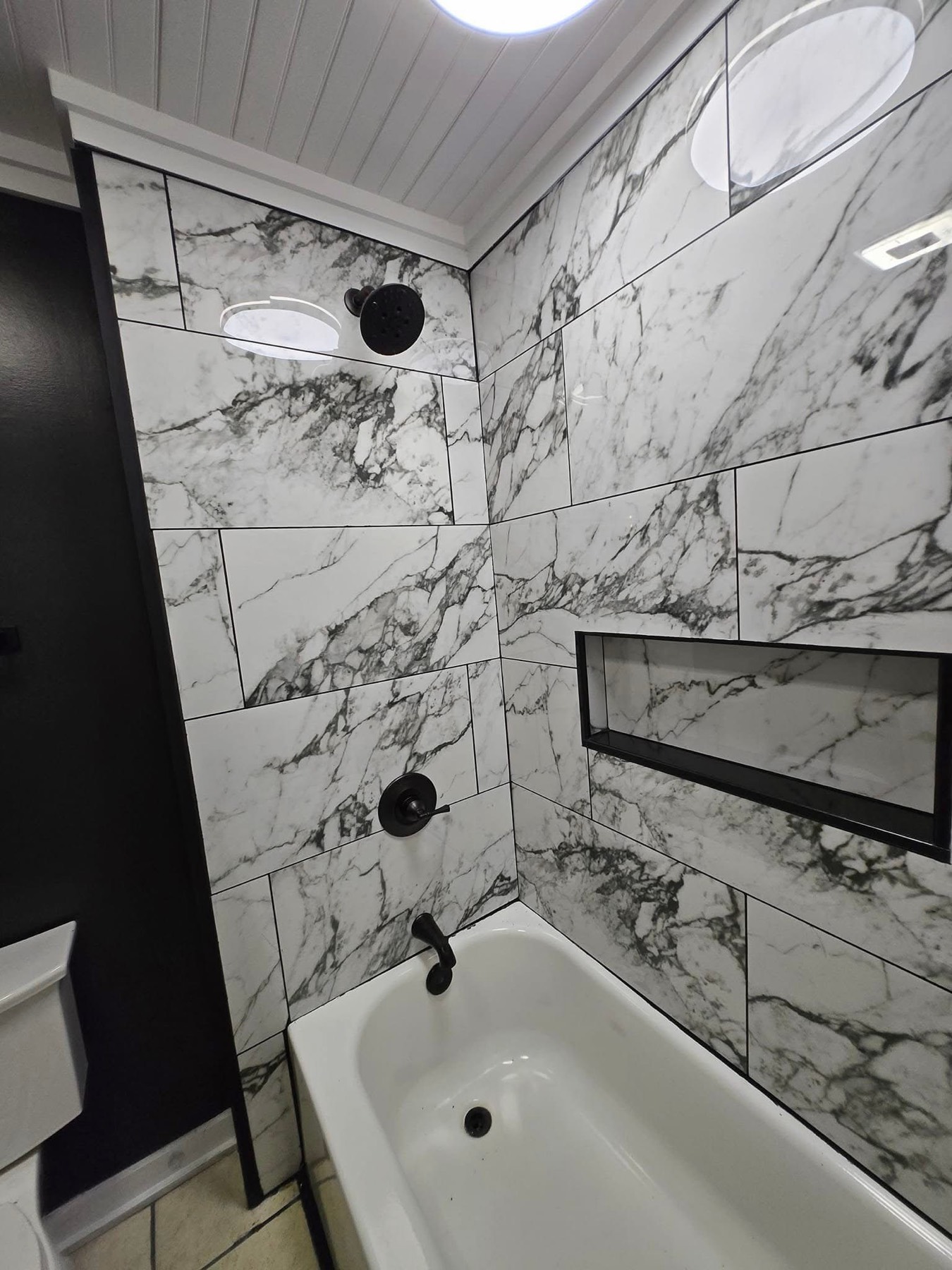 Tub surround in marble-look tile, black fixtures