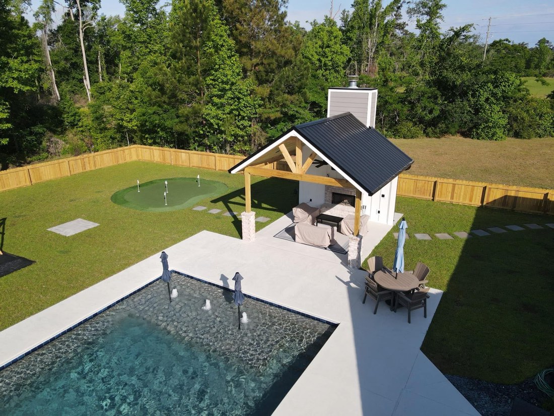 Backyard with in-ground pool, putting green, and custom pavilion with outdoor fireplace